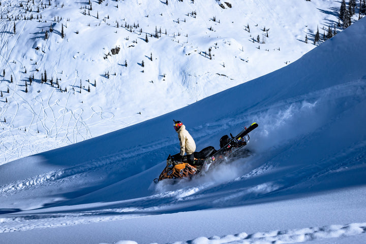 snowmobile bracket kit in action. Snowmobiler going down a snowy hill with skies on his sled